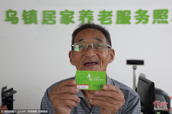 80歲的陳叔良老人在工作人員的指導下辦理樂享生活卡。他憑借此卡便可享受照料中心提供的線上線下服務。 (圖片作者：沈志成)